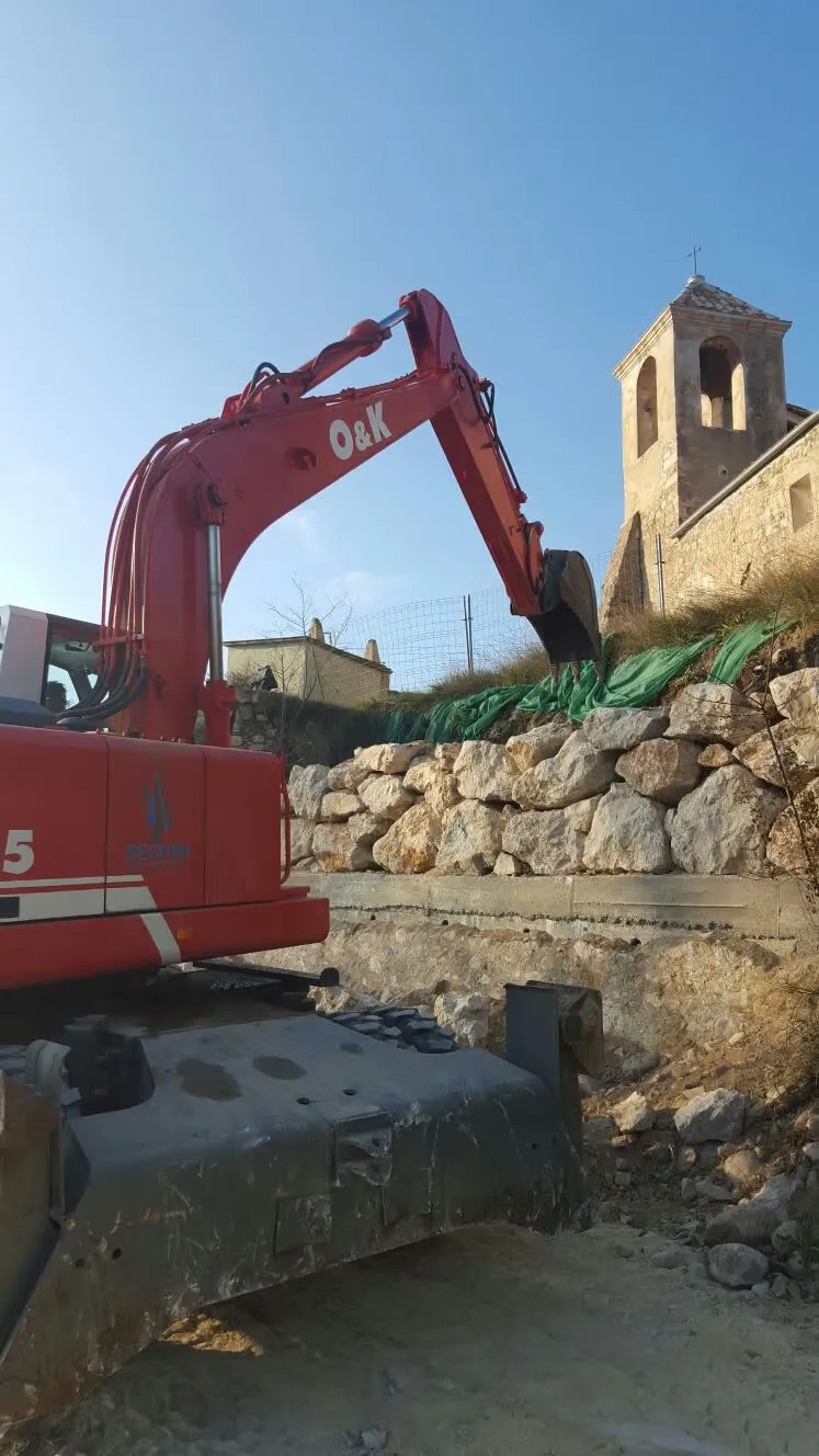 Excavadora colocando piedra natural para una escollera junto a la Iglesia de Besalú
