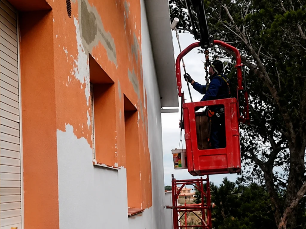 Operario de SECOMI rehabilitando la fachada de un edificio en Cala Rovellada, Colera