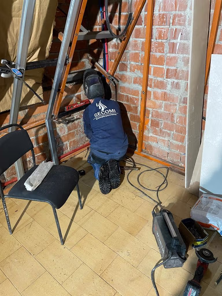 Trabajos de refuerzo metálico junto a un cerramiento de ladrillo en una vivienda