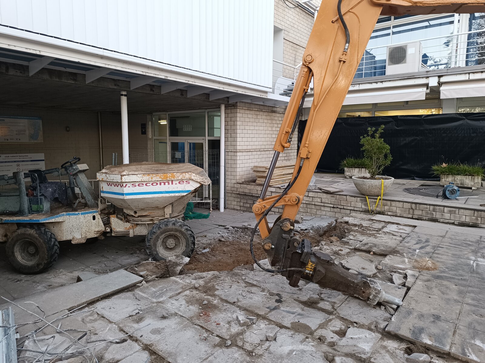 Miniexcavadora y dúmper de SECOMI retirando el pavimento del patio de acceso al club