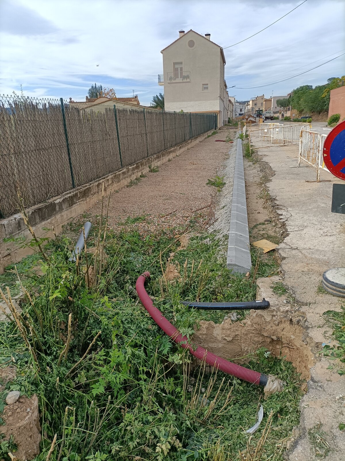 Zanja con el tubo de canalización del alumbrado público y el bordillo nuevo ya colocado
