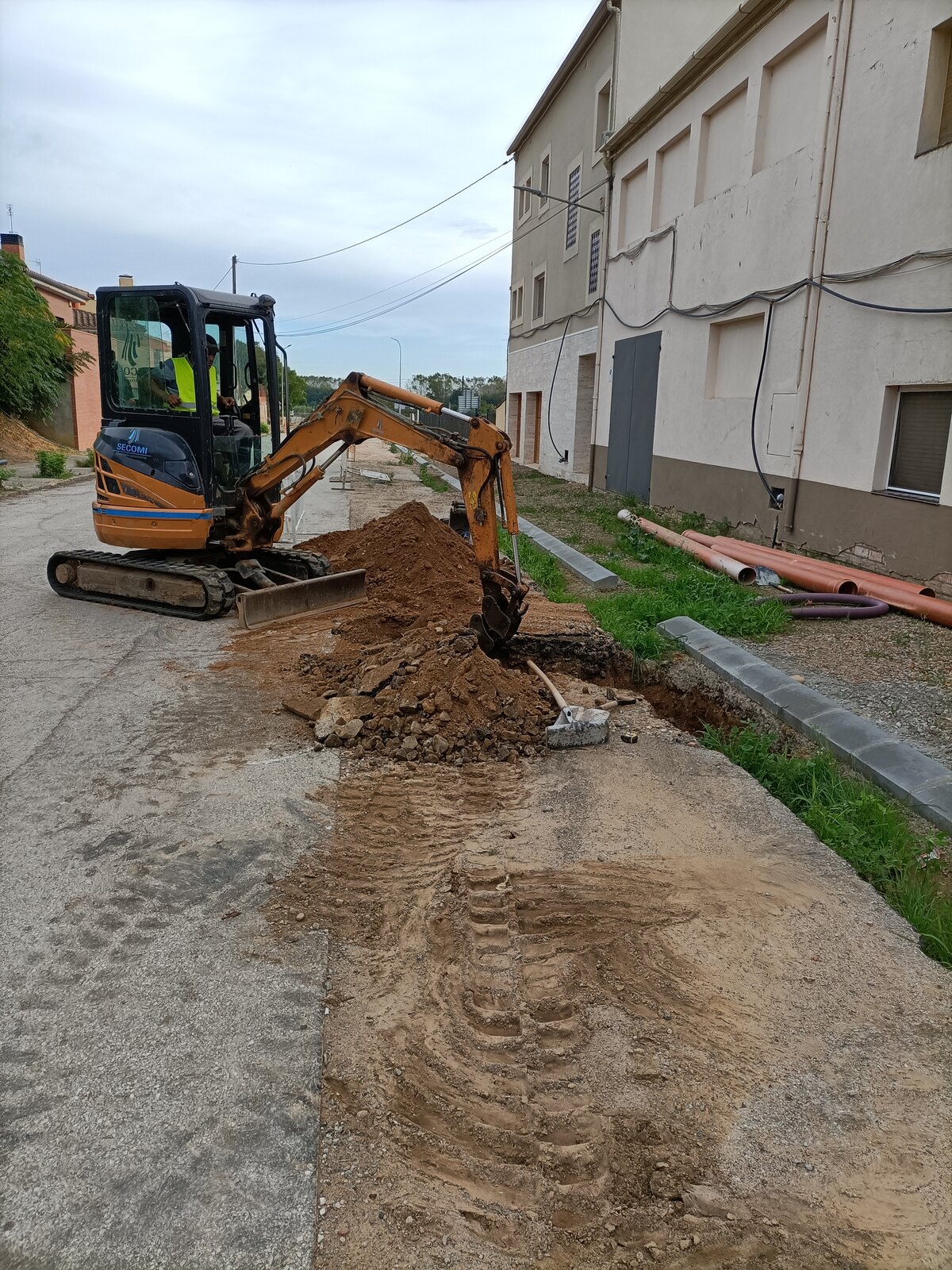Excavación del terreno junto al bordillo nuevo de la acera, en Medinyà