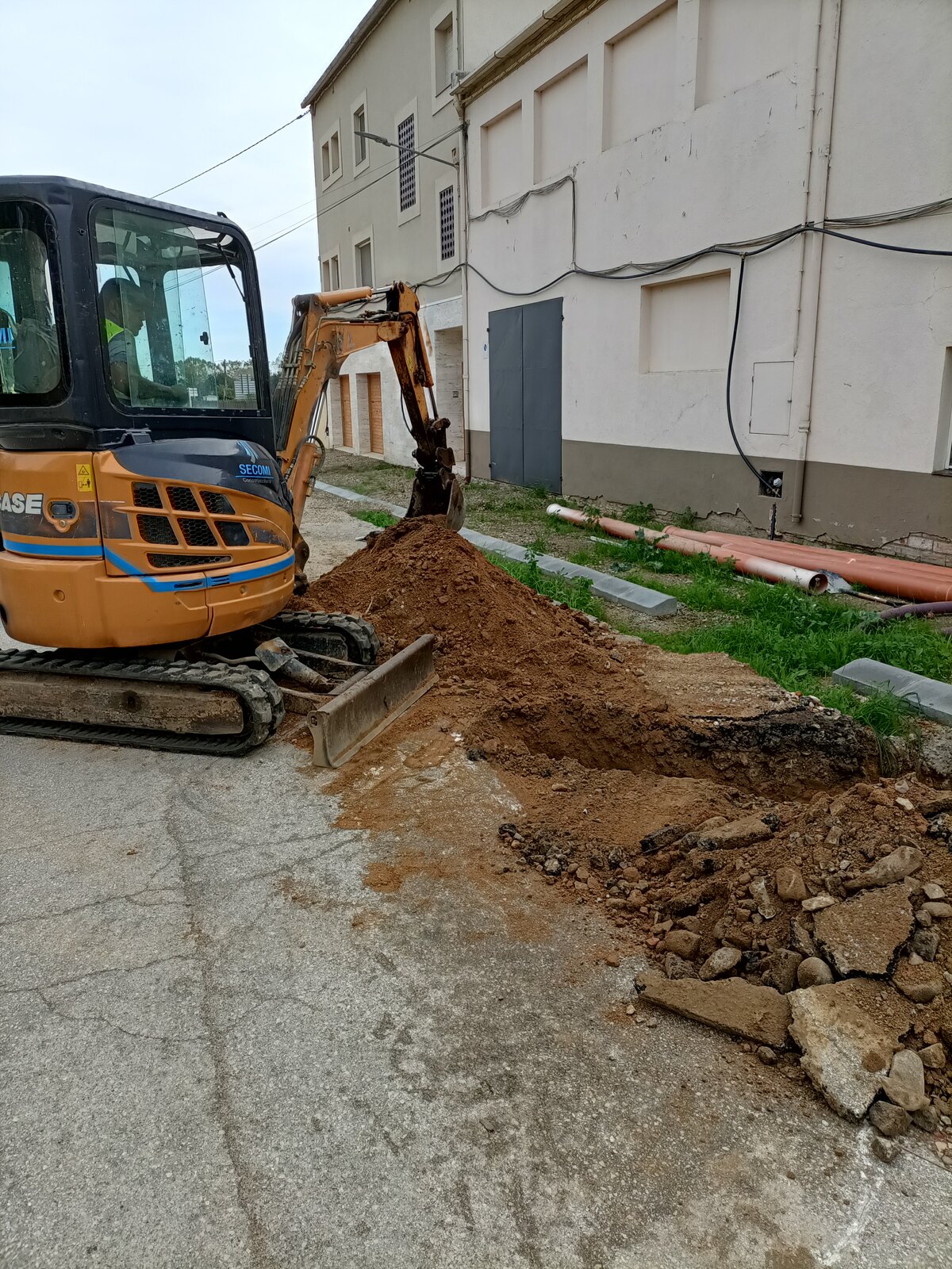 Miniexcavadora abriendo la zanja junto a las fachadas del carrer Dr. Fleming