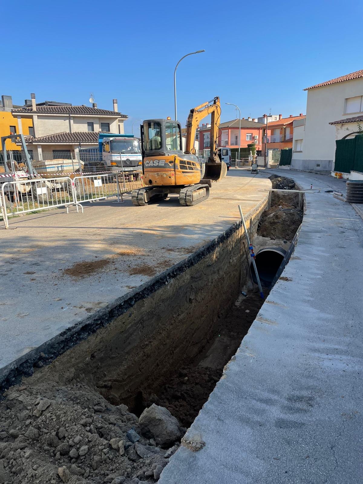 Zanja abierta con la tubería de saneamiento y la solera de hormigón de la acera ejecutada