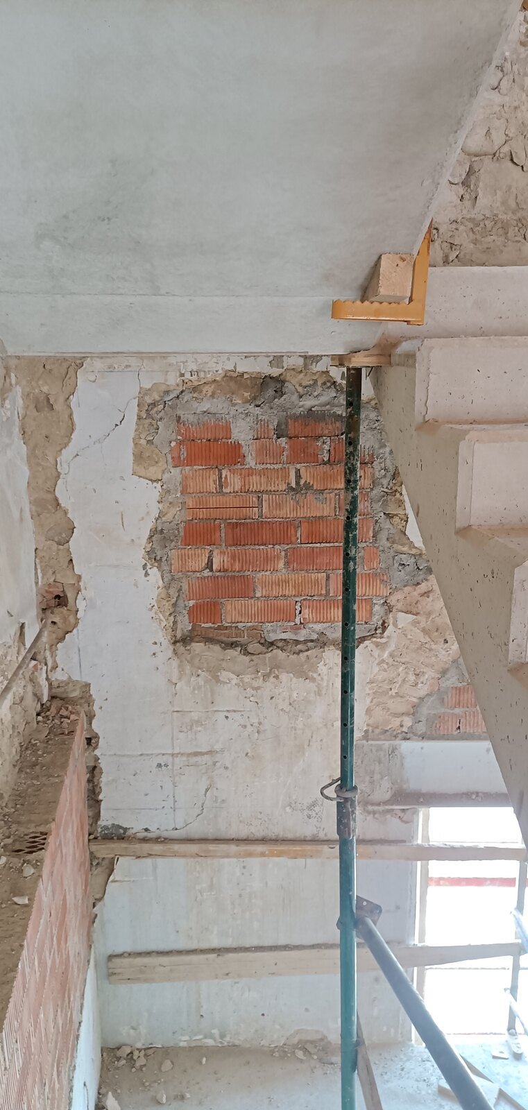 Escalera de hormigón de nueva ejecución adosada al muro de piedra existente de la vivienda