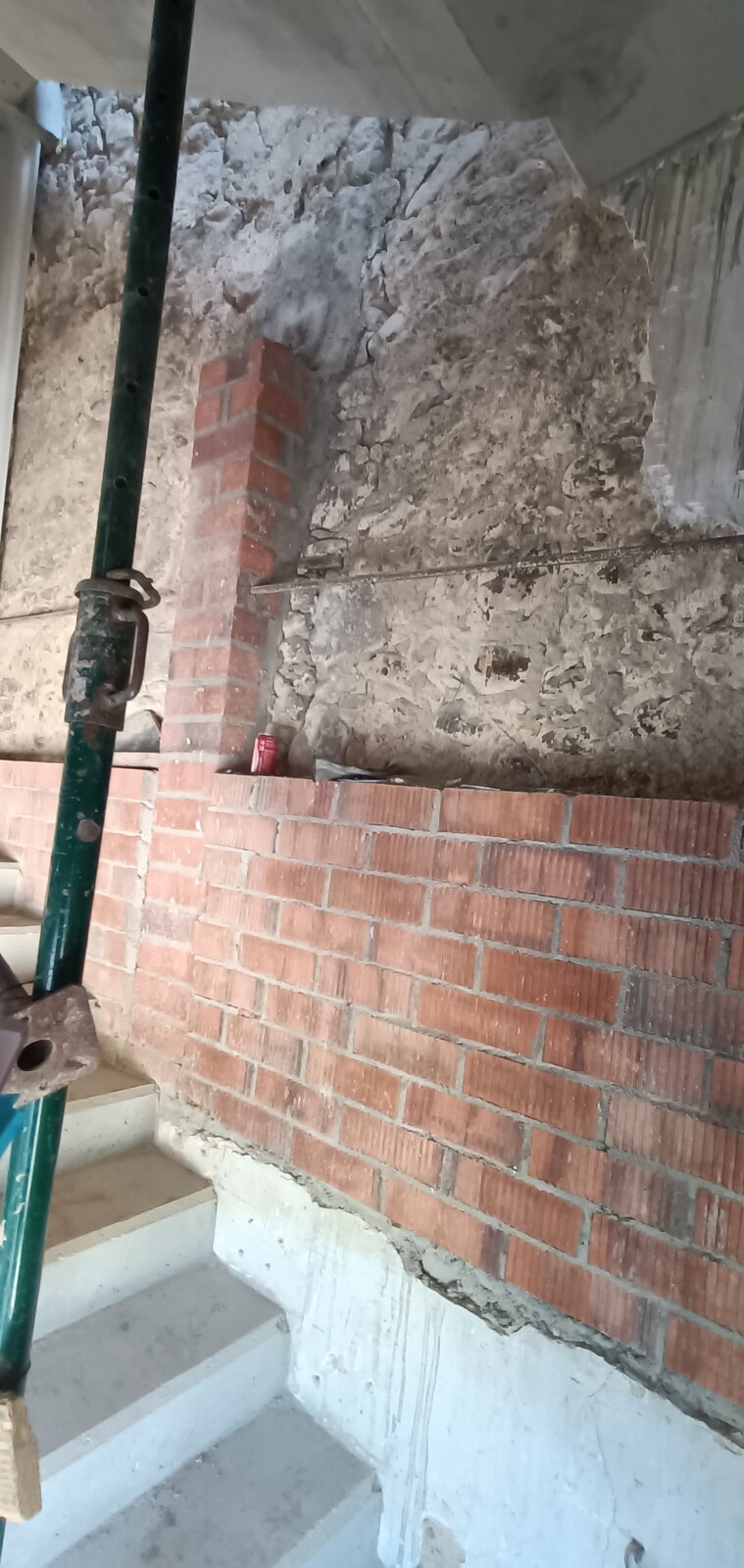 Pilar de ladrillo de obra nueva levantado junto a la escalera de hormigón de la vivienda de Mieres